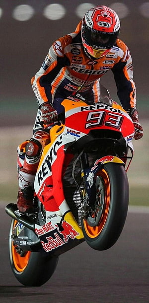 Marc Marquez performing a wheelie on a Repsol Honda motorcycle during a night race HD phone wallpaper