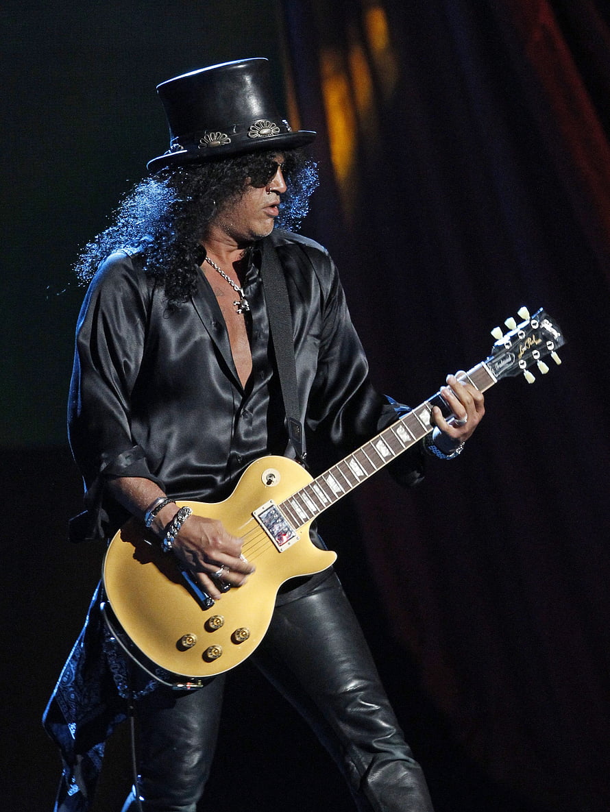 Slash performing live on stage in a black top hat and satin shirt with a gold Gibson Les Paul guitar HD phone wallpaper