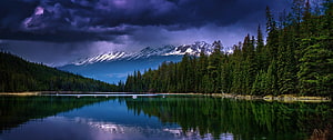 Dramatic Alpine Lake Reflection Under Stormy Purple Skies and Snow-Capped Peaks HD wallpaper