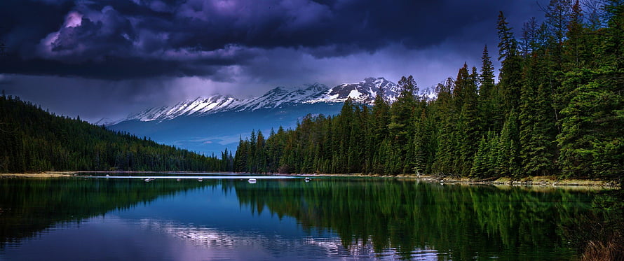 Dramatic Alpine Lake Reflection Under Stormy Purple Skies and Snow-Capped Peaks HD wallpaper