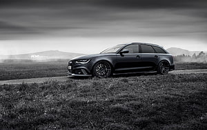 Black Audi RS6 Avant Station Wagon Parked on Grassy Field Under Dramatic Sky HD wallpaper