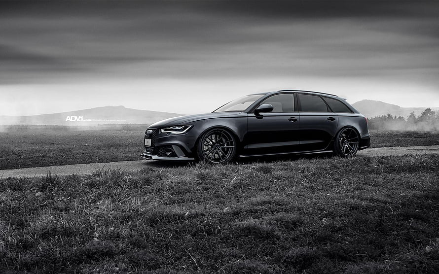 Black Audi RS6 Avant Station Wagon Parked on Grassy Field Under Dramatic Sky HD wallpaper
