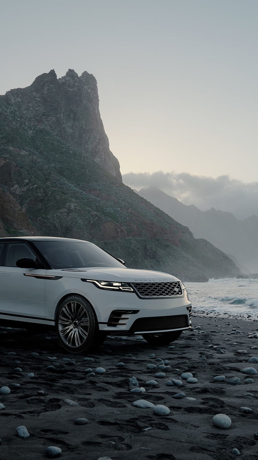 White Range Rover Velar parked on a pebble beach with dramatic coastal cliffs in the background HD phone wallpaper