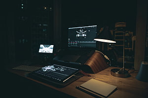 Moody Home Office Setup with Laptop, Tablet, and Desk Lamp at Night HD wallpaper