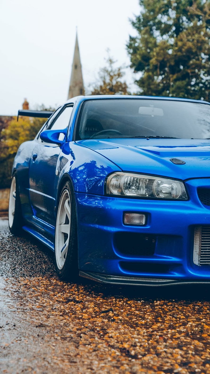 Blue Nissan Skyline GT-R R34 with White Wheels Parked on Gravel Road HD phone wallpaper