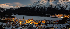 Illuminated Swiss Alpine Village at Dusk with Frozen Lake and Snow-Capped Mountains HD wallpaper