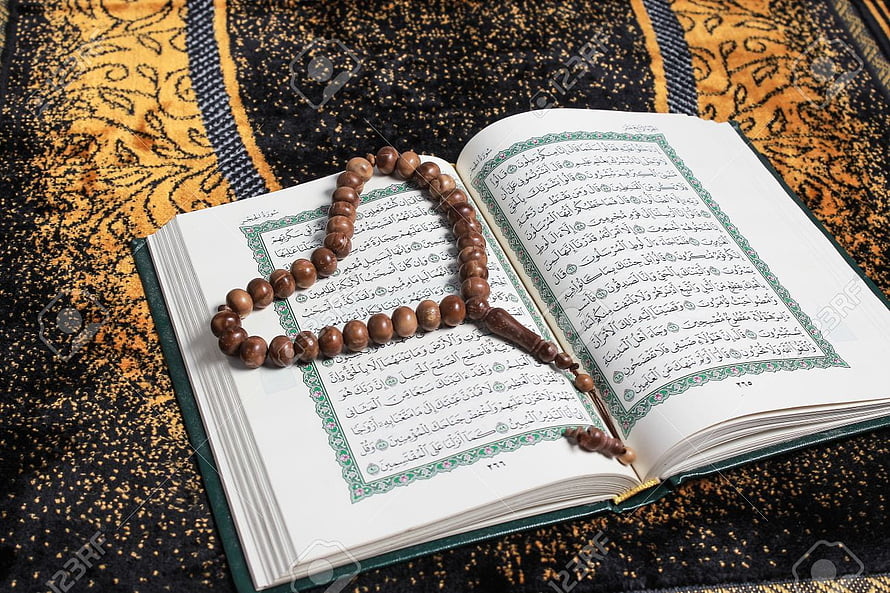 Open Quran with wooden prayer beads resting on ornate prayer mat HD wallpaper
