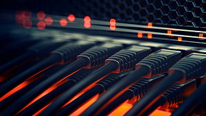 Close-up of network switch ports with glowing red indicator lights and ethernet cables in a data center HD wallpaper