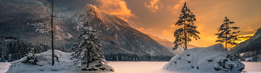 Snow-Covered Alpine Lake at Golden Hour with Pine Trees and Mountain Peaks HD wallpaper