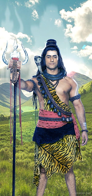 Lord Shiva in tiger skin with trident and cobra in a green mountain landscape HD phone wallpaper