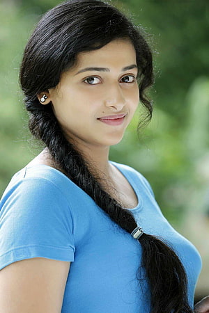 Anu Sithara Portrait in Blue Top with Long Braid and Green Background HD phone wallpaper