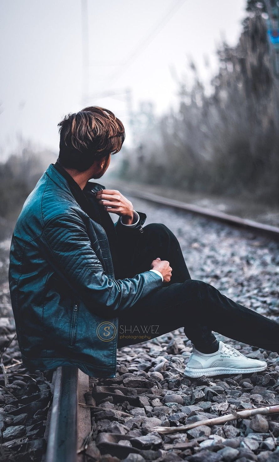Young man in teal leather jacket sitting on railway tracks in a contemplative pose, Boys dp, sad pose boy HD phone wallpaper