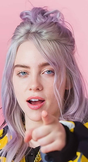 Billie Eilish Portrait with Lavender Hair and Pointing Gesture on Pink Background HD phone wallpaper