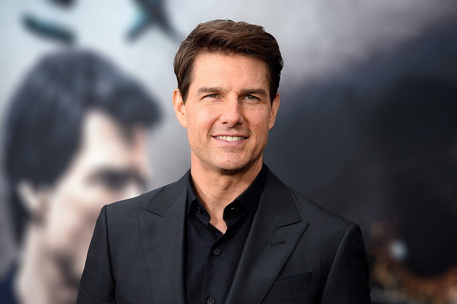 Tom Cruise in a black suit and shirt smiling at a promotional event HD wallpaper