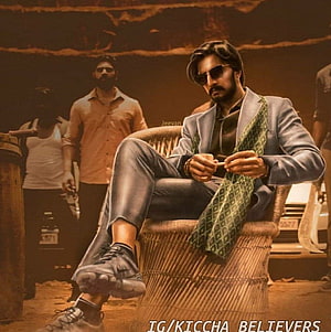 Kiccha Sudeepa in a stylish blue suit and sunglasses seated in a wicker chair with a green scarf HD phone wallpaper