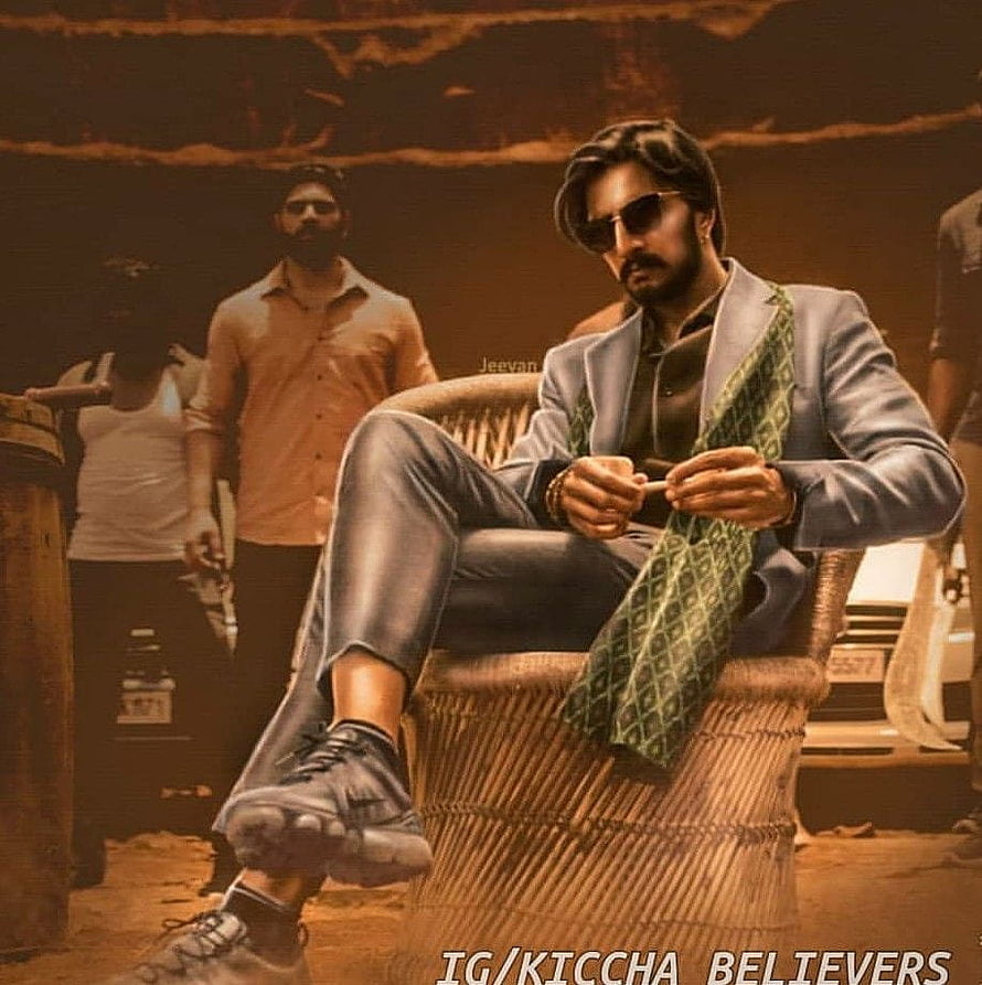 Kiccha Sudeepa in a stylish blue suit and sunglasses seated in a wicker chair with a green scarf HD phone wallpaper