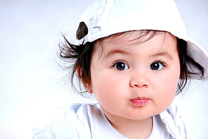 Adorable Baby Boy Wearing A White Cap With A Playful Expression HD wallpaper