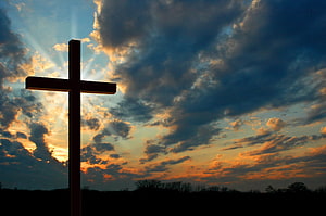 Silhouetted Christian Cross Against Dramatic Sunset Sky With Golden Clouds HD wallpaper