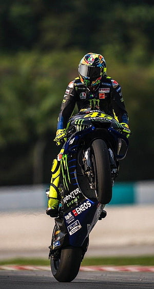 Valentino Rossi performing a wheelie on his Yamaha MotoGP bike with Monster Energy livery HD phone wallpaper