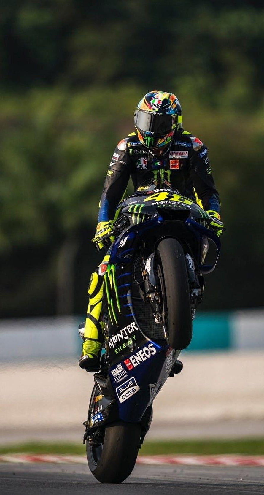 Valentino Rossi performing a wheelie on his Yamaha MotoGP bike with Monster Energy livery HD phone wallpaper