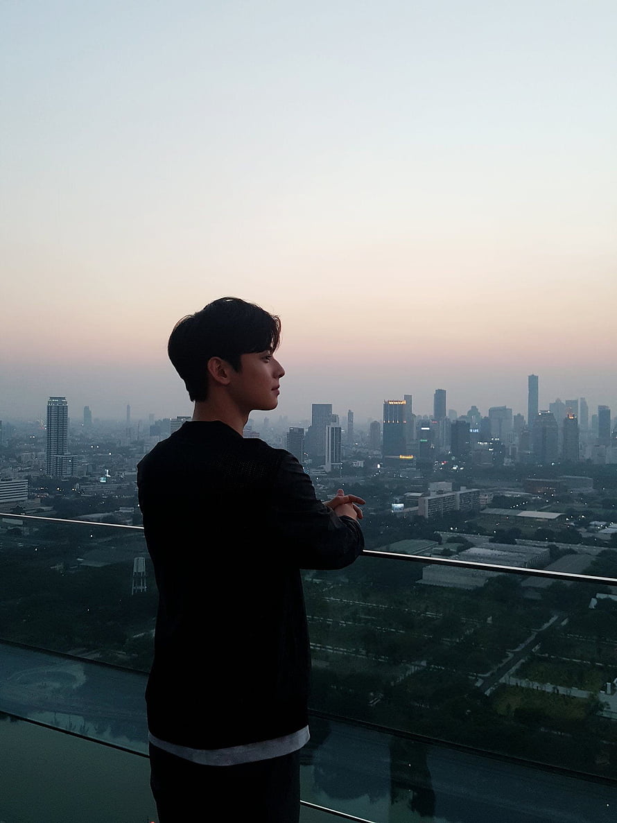 Cha Eun Woo on a rooftop terrace overlooking a city skyline at dusk HD phone wallpaper