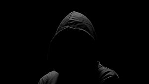 Silhouette of a person in a dark hooded jacket against a black background HD wallpaper