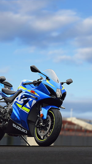 Blue Suzuki GSX-R 1000 sportbike parked on asphalt under a bright blue sky with scattered clouds HD phone wallpaper