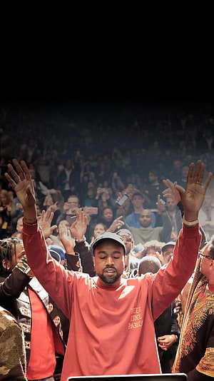 Kanye West performing live with arms raised before a large concert crowd HD phone wallpaper