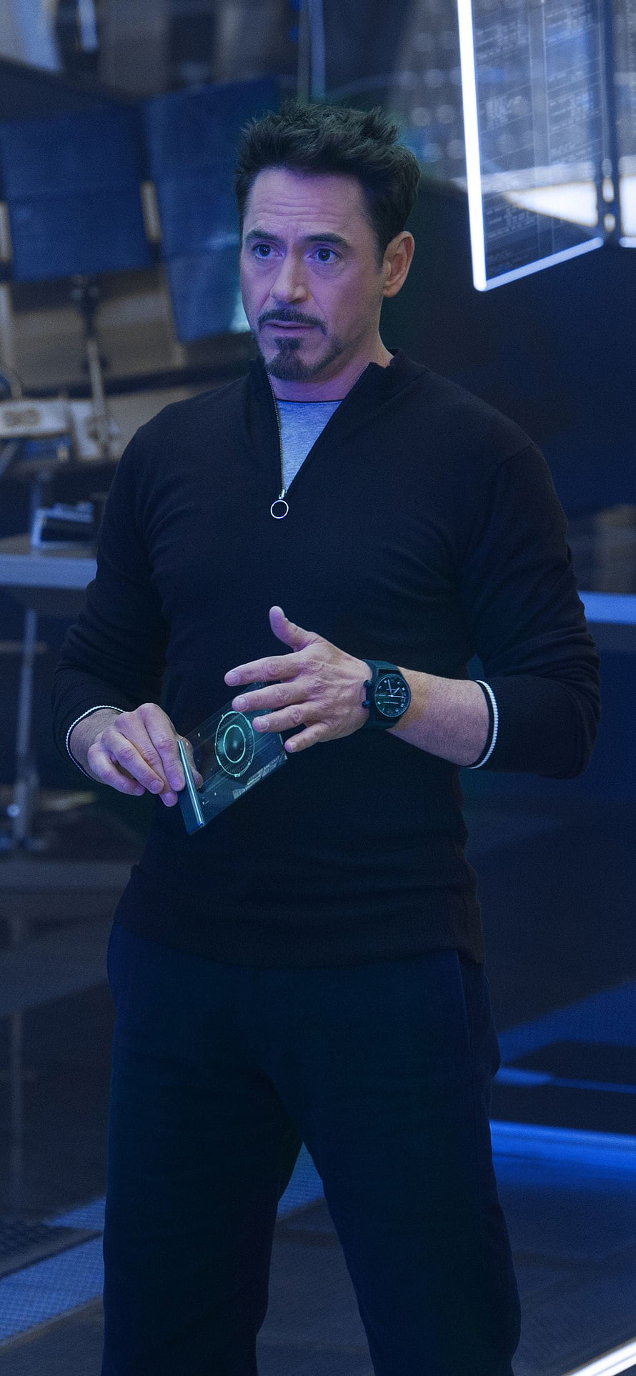 Tony Stark in a High-Tech Lab Holding a Futuristic Device HD phone wallpaper