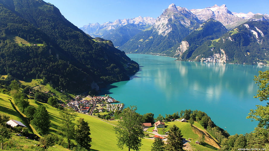 Aerial View of a Turquoise Alpine Lake Nestled Among Green Hills and Snow-Capped Swiss Mountains HD wallpaper