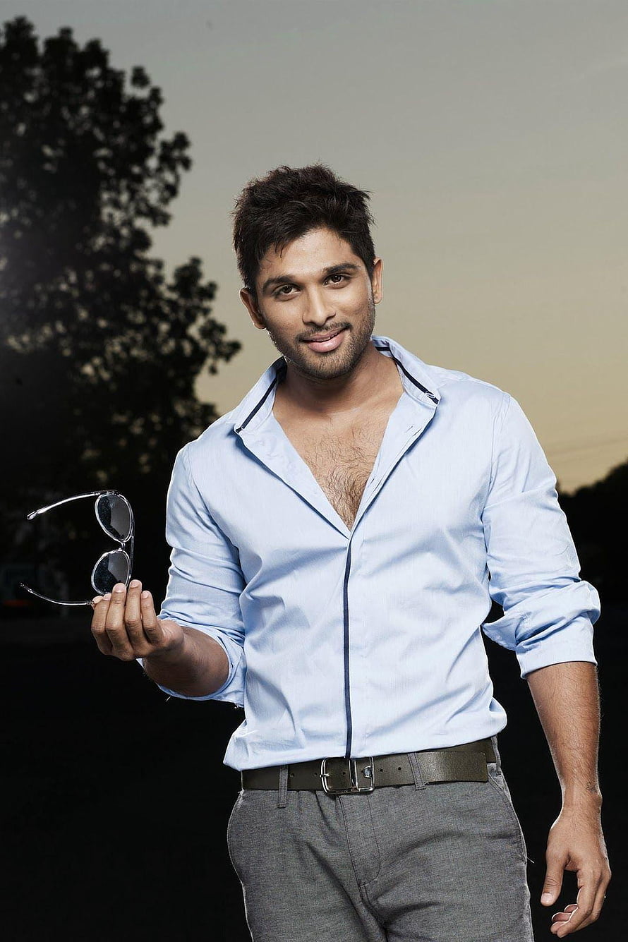 Allu Arjun in a light blue shirt holding sunglasses against a sunset backdrop HD phone wallpaper