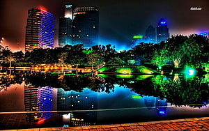 Vibrant Night Cityscape with Illuminated Skyscrapers and Lake Reflections HD wallpaper