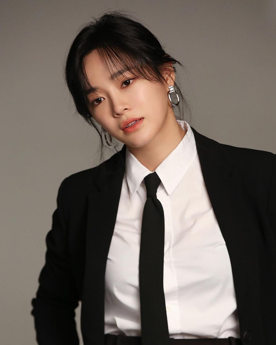 Kim Se Jeong in a black blazer, white shirt, and black tie with hoop earrings against a neutral studio background HD phone wallpaper