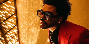 The Weeknd in a red suit and sunglasses against a warm golden bokeh background HD wallpaper