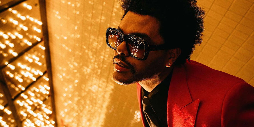The Weeknd in a red suit and sunglasses against a warm golden bokeh background HD wallpaper