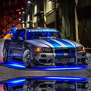 Nissan Skyline GT-R R34 with Blue Underglow and Racing Livery Parked at Night HD phone wallpaper