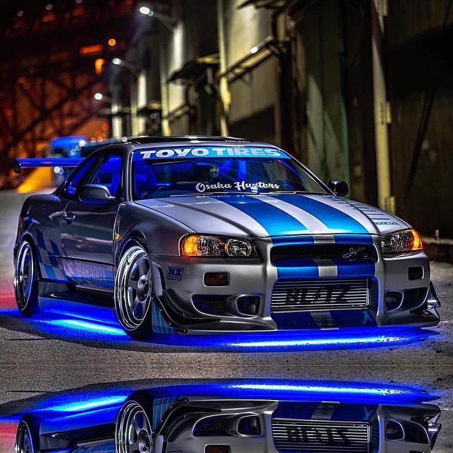 Nissan Skyline GT-R R34 with Blue Underglow and Racing Livery Parked at Night HD phone wallpaper