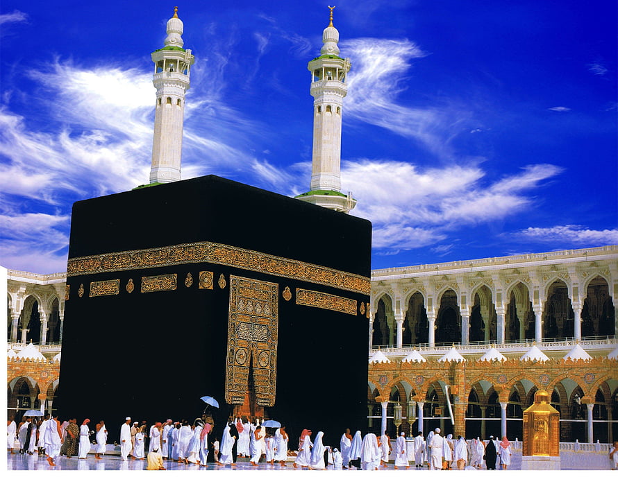The Kaaba in Mecca with pilgrims and minarets under a bright blue sky HD wallpaper