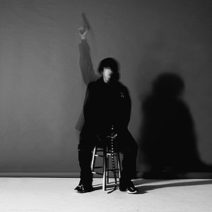 DPR Ian Black and White Portrait Sitting on Stool with Raised Arm and Dramatic Shadow HD phone wallpaper