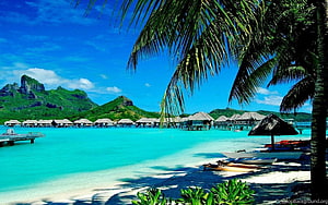 Tropical Overwater Bungalows on a White Sand Beach with Turquoise Water and Lush Green Mountains HD wallpaper