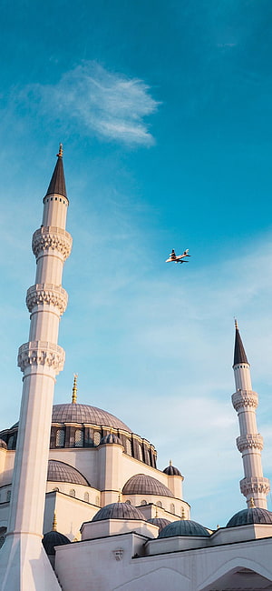 Sultan Ahmed Mosque in Istanbul with a jet flying overhead against a clear blue sky HD phone wallpaper