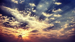 Dramatic sunset sky with radiant sunbeams breaking through scattered clouds HD wallpaper