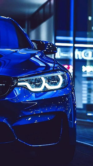 Blue BMW M4 Front Headlight Close-Up in Neon-Lit Urban Night Setting HD phone wallpaper