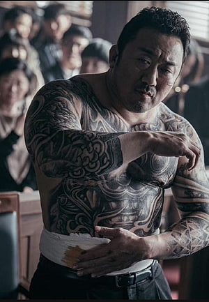 Ma Dong Seok shirtless with full body tattoos and bandaged abdomen in dramatic cinematic scene HD phone wallpaper