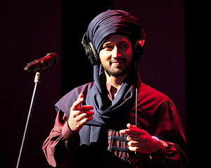 Atif Aslam performing live on stage wearing a turban and headphones under red lighting HD wallpaper