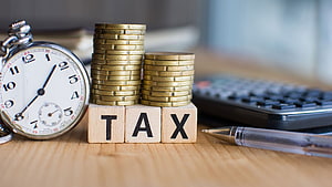 Income Tax Planning Concept with Stacked Coins, Stopwatch, and Calculator on Desk HD wallpaper