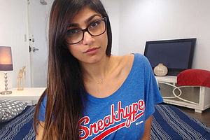 Mia Khalifa in a blue SneakHype t-shirt and black-framed glasses in a bedroom setting HD wallpaper