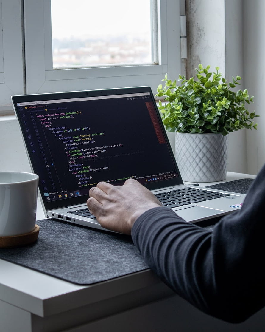 Web Developer Coding on Laptop at a Bright Home Desk with Plant and Coffee HD phone wallpaper