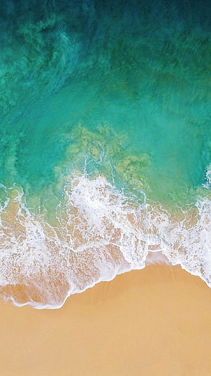 Aerial View of Turquoise Ocean Waves Lapping Against Golden Sandy Beach HD phone wallpaper