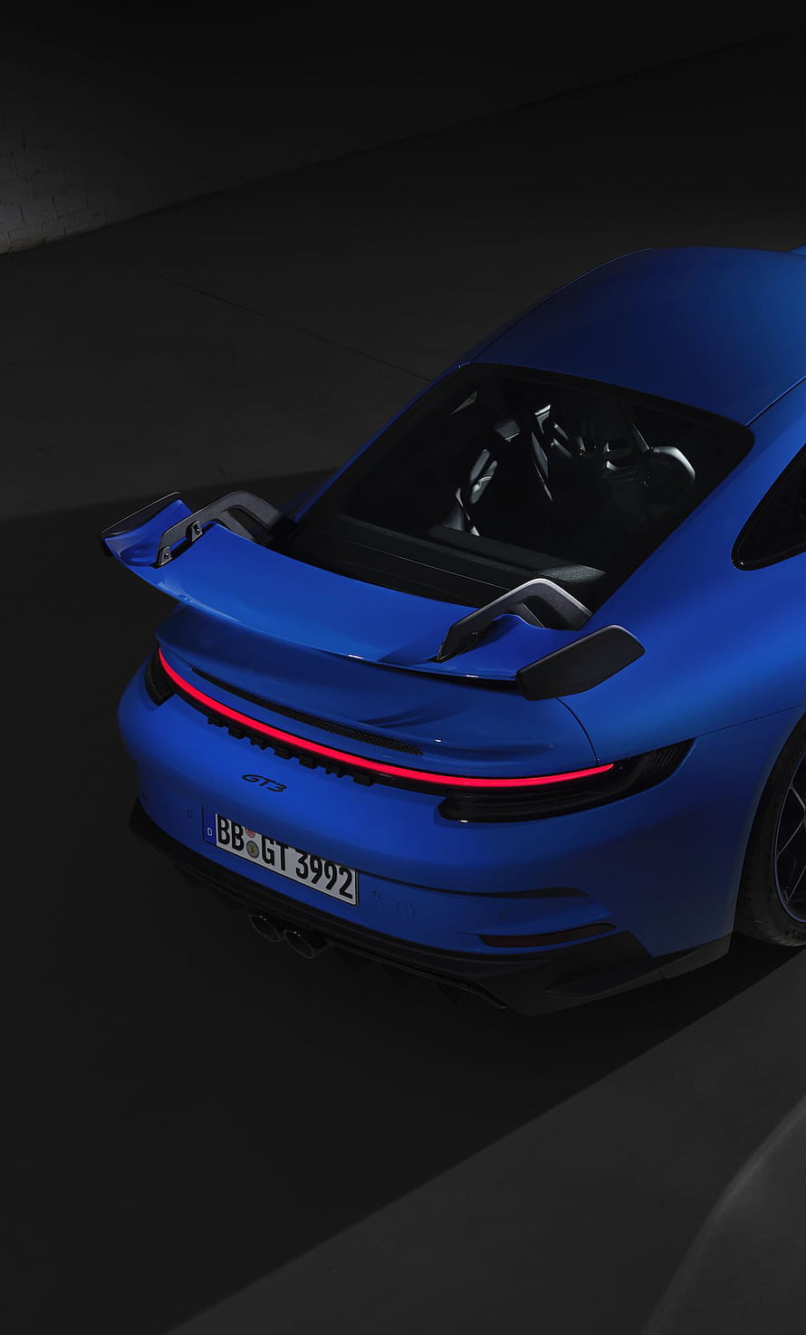 Rear View of a Blue Porsche 911 GT3 with Prominent Spoiler and LED Taillights in a Dark Studio Setting HD phone wallpaper